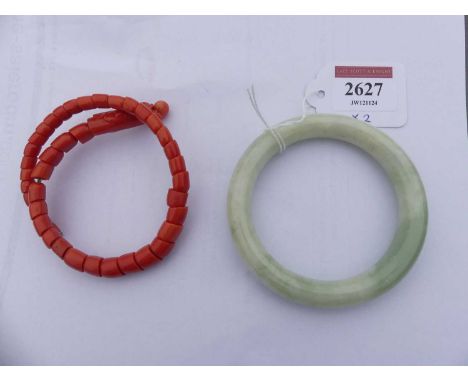 A plain pale celadon nephrite bangle, 75g, dia.8.5cm; together with a coral snake bangle, on sprung metal shaft, 37.5g (2)Bot
