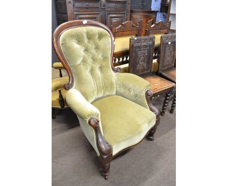 A Victorian green button upholstered armchair with scrolled arms and turned legs