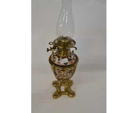 A late 19th Century oil lamp with pottery body, the reservoir enclosed with brass cover raised on four claw feet complete wit