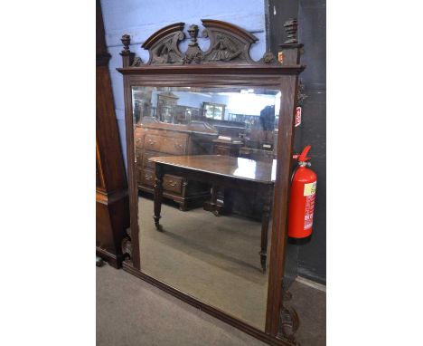 A late Victorian over mantel mirror of large proportions, the mahogany frame with broken arch pediment with carved floral and