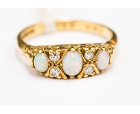 A three opal stone ring with four small diamonds set .750,18 carat yellow gold