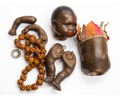 A German porcelain Heubach koppel black doll, modelled as an African child in native dress with ankle bangle and hoop earring