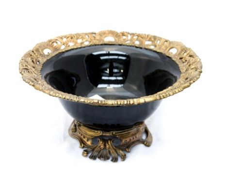 A large black ceramic bowl, having a pierced brass footted foliate base, and a pierced brass floral and foliate rim