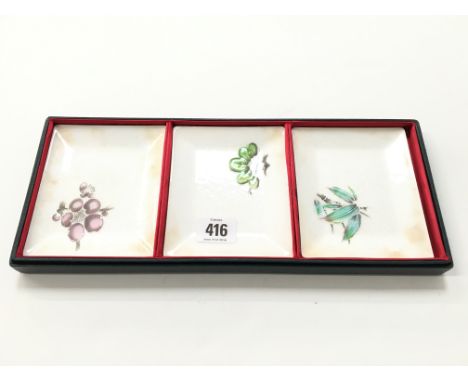 A set of three Chinese enamel metal saucer dishes decorated with leaves and fruit.