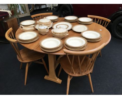 An Ercol elm Windsor light finish large gate-leg table on beech supports together with four Chilton candlestick design chairs