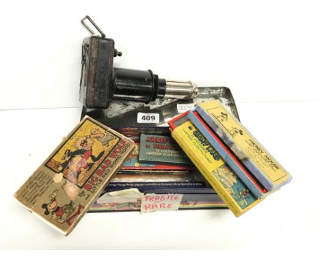 A tin containing an early 20th century lantern slide projector together with various Mickey Mouse slide sets.