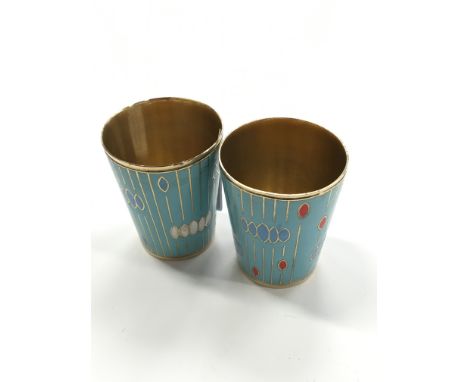 A pair of continental white metal enamel decorated vodka cups.