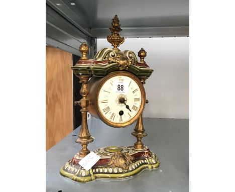 An early 20th century German china cased mantle clock with brass urn finial and side columns and drum brass movement by Lenzk