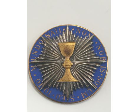 A gilt metal and enamel badge decorated with a chalice and inscribed 'Non Nobis Solum Sed Toto Mundo Nati'