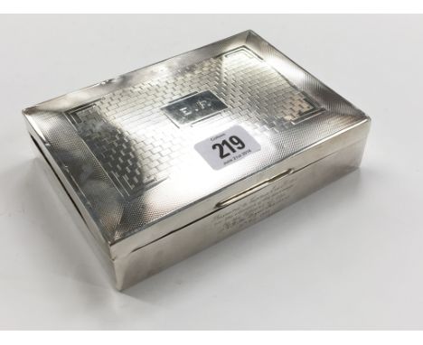 A large silver cigarette box with engine turned brickwork decoration to lid, presentation inscription to front dated 1935.