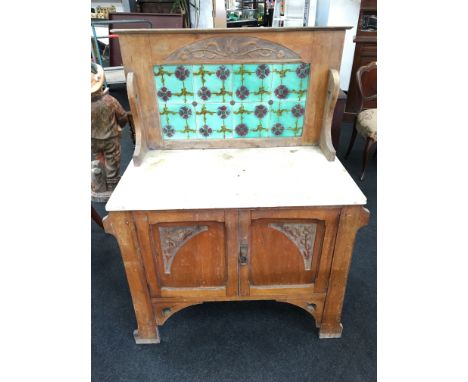 An Art Nouveau satin walnut washstand fitted with marble top and tile back, resting on outswept legs.