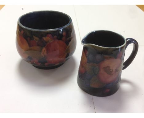 A Moorcroft pomegranate pattern milk jug and sugar basin, each decorated to a dark blue ground, painted and impressed marks (
