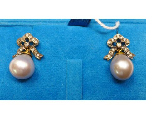 A boxed pair of 18ct yellow gold earrings, with diamond-studded bow tops each suspended by a pear-shaped grey cultured pearl,