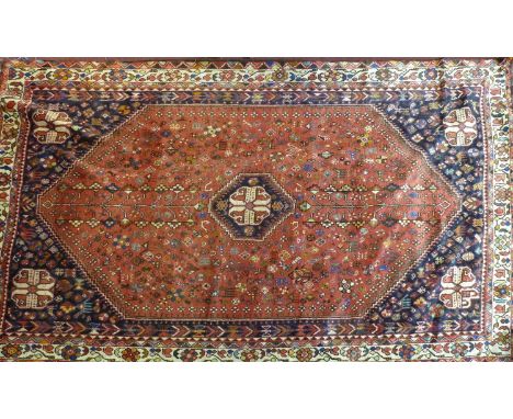 A South West Persian Qashqai carpet, central diamond medallion with repeating petal and animal motifs on a terracotta field, 