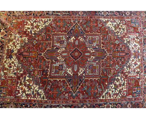 A North West Persian Heriz carpet, central diamond medallion with repeating geometric motifs on a rouge field, within stylise