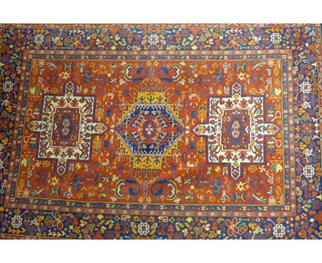 A Heriz carpet with three geometric medallions, on a red and blue ground, contained by geometric borders, 302 x 201cm 