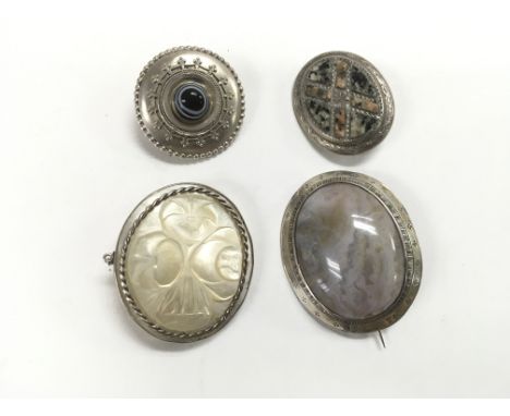Four white metal brooches comprising one set with mother of pearl and three others set with polished stones. Possibly Scottis
