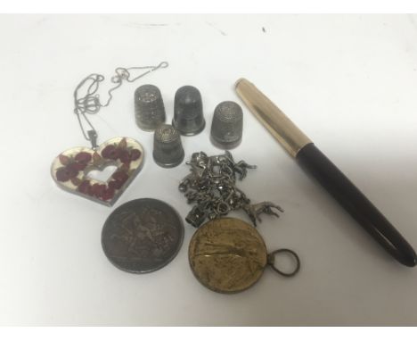 A collection of items comprising silver charm bracelet silver thimbles a fountain pen a 1900 crown and a I world war medal aw