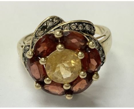 A 9ct gold ring set with citrine, garnet and diamonds. The approximate ring size is N.