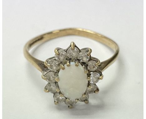 A 9ct gold ring set with a central opal and surrounded by clear stones, the approximate ring size is between o and p.