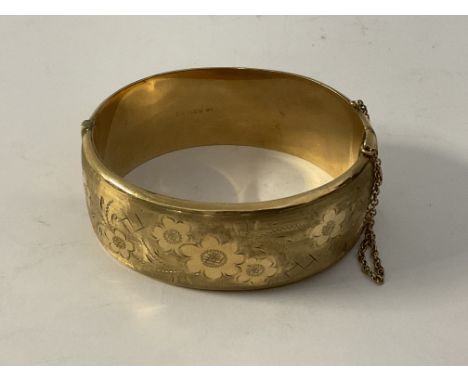 A 9ct gold hallmarked bangle with floral decoration.