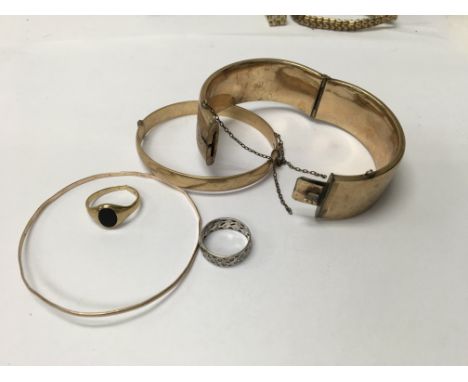A gold bangle together with signet ring together with to other bangle s and a ring .