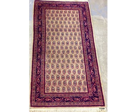 A small side carpet in pink and beige 135 x 72cm