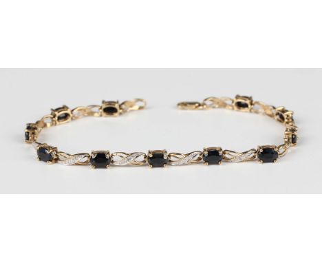 A 9ct gold, sapphire and diamond bracelet, claw set with a row of oval cut sapphires alternating with scrolled links, on a sp