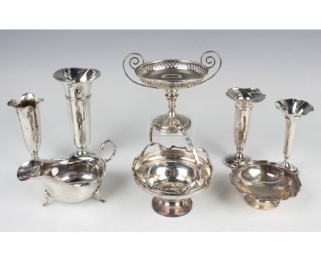 A George V silver circular bonbon basket with pierced swing handle above a cast scrolling naturalistic rim, on a circular foo