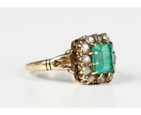 A gold, emerald and diamond cluster ring, early 20th century, claw set with the rectangular step cut emerald within a surroun