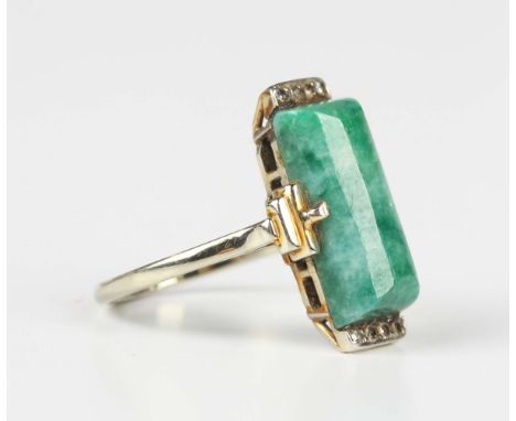 An Art Deco white gold ring, mounted with a central baton shaped jade between diamond four stone set sides, detailed '18ct', 