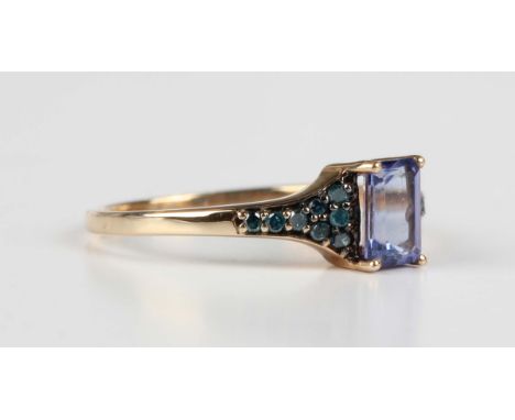 A 9ct gold ring, claw set with a rectangular step cut tanzanite between treated blue diamond set shoulders, Birmingham 2012, 