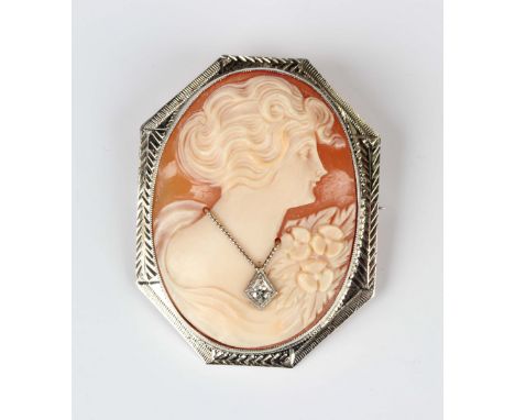 A white gold mounted oval shell cameo brooch, carved as a portrait of a lady wearing a pendant necklace, mounted with a circu