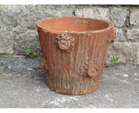 An old weathered terracotta planter of circular tapered form with simulated combed tree bark/dug out trunk effect, 32 cm diam