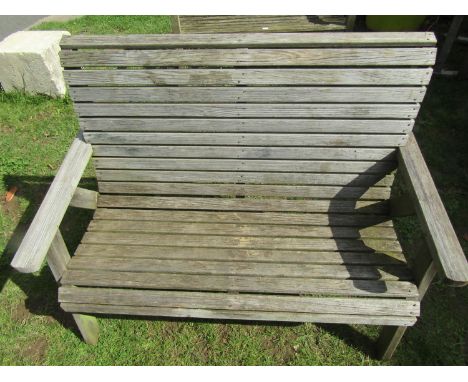 A weathered two seat wooden garden bench with slatted seat and combined back raised on A framed supports, 120cm wide 