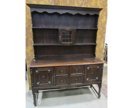 An Edwardian oak dresser in the Jacobean style, with two central drawers flanked by two cupboards with carved and applied mou