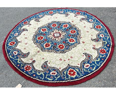 A circular hand knotted carpet of Middle Eastern design of a central floral medallion with a floral border on a blue ground 1