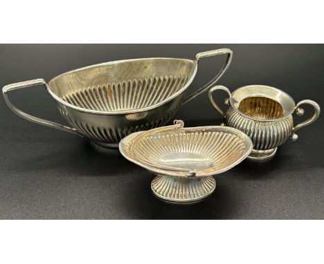 A solid silver salt bowl, half flute design with twin handles, Chester together with two similar smaller Birmingham pieces, v