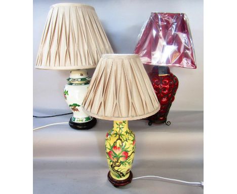 A red glass table lamp with an overlaid metal scrolled frame and a pleated red shade, another lamp with prunus and blossom de