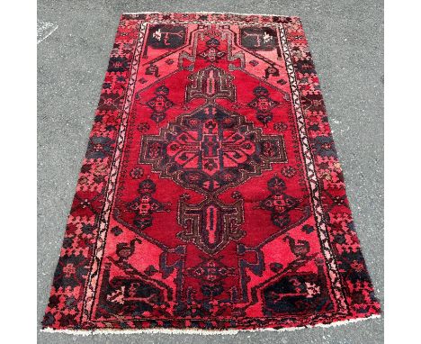 A Middle Eastern carpet with an extended central medallion on a predominantly red ground 183  cm x 144 cm 
