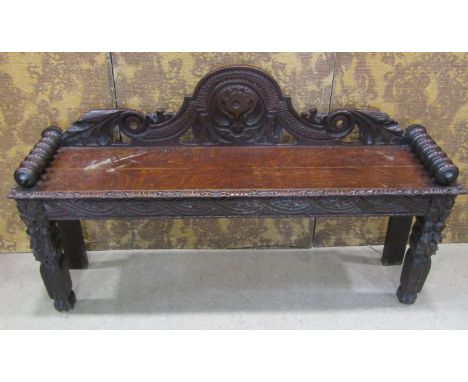 A Victorian oak hall bench with carved and pierced back, scrolled arms, carved supports, 130cm diameter 