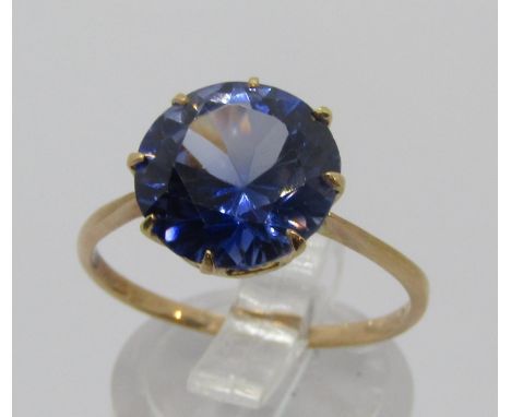 Yellow metal ring claw set with a violet-blue synthetic sapphire, maker 'SMB', size R, 2.9g (see photograph of 2012 insurance