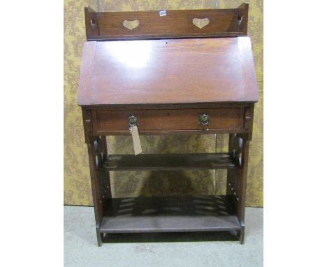 An arts and crafts oak writing bureau, the fall flap enclosing a fitted interior over a frieze drawer with open shelf below, 