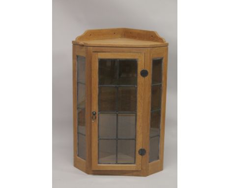 ROBERT "MOUSEMAN" THOMPSON. AN OAK HANGING CORNER CABINET, with a single leaded glazed door opening to reveal three glass she