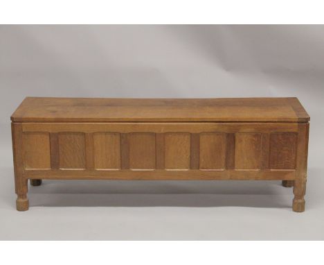 ROBERT "MOUSEMAN" THOMPSON. AN OAK OTTOMAN, with an adzed rectangular rising top, panelled front and ends on shaped feet. 4ft