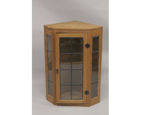 ROBERT "MOUSEMAN" THOMPSON. AN OAK HANGING CORNER CABINET, with a single leaded glazed door opening to reveal three glass she