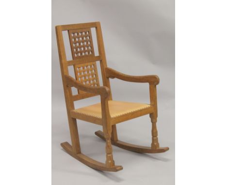 ROBERT "MOUSEMAN" THOMPSON. AN OAK ROCKING CHAIR with double lattice panel back, curving arms, close nailed tan leather seat 