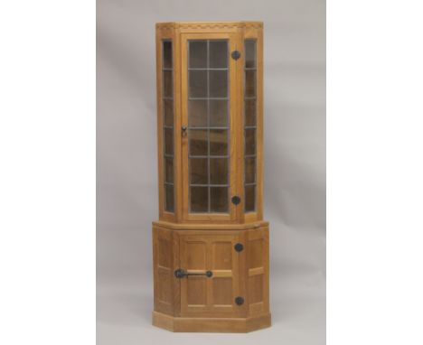 ROBERT "MOUSEMAN" THOMPSON. AN OAK STANDING CORNER CABINET, the upper section with a leaded glazed door, flanked by a pair of