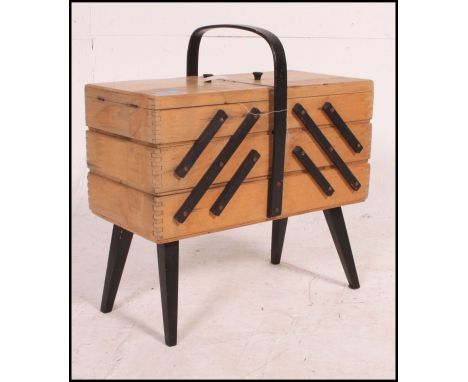 A vintage 1950's metamorphic sewing box raised on tapered legs with multi-sectional hinged top.