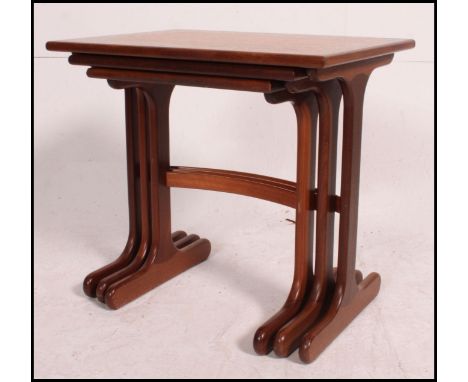 A 1970's retro teak wood Danish influence nest of tables having bow stretchers with graduating tops to each